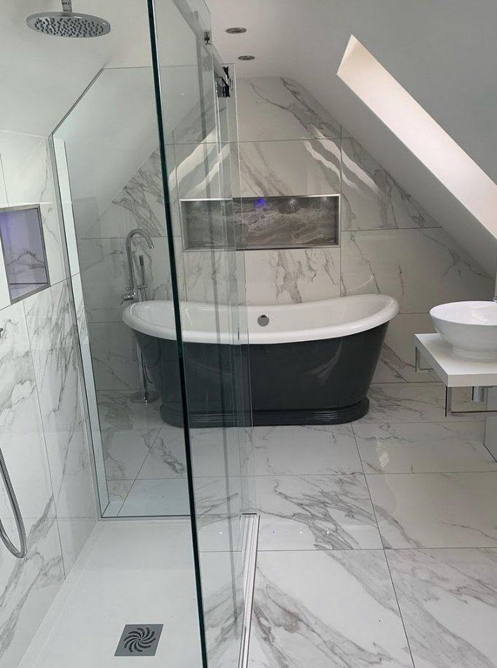 Attic bathroom with large marble-look porcelain tile on the walls and floor, a charcoal freestanding tub, vessel sink and frameless glass shower